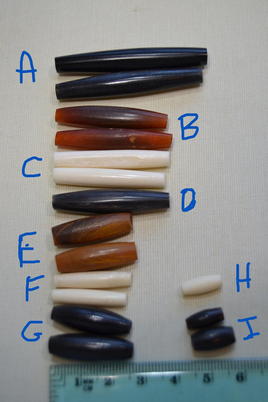 Solid colored hair pipe beads, bone or horn, loose in groups.